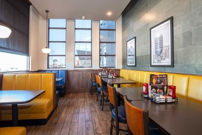 Framed pictures on the wall and condiments on tables in Denny’s Restaurant at Sandman Hotel & Suites Winnipeg Airport