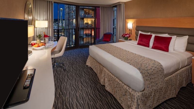 A luxurious hotel room with a large bed, balcony, desk, and modern amenities at Warwick Hotels and Resorts