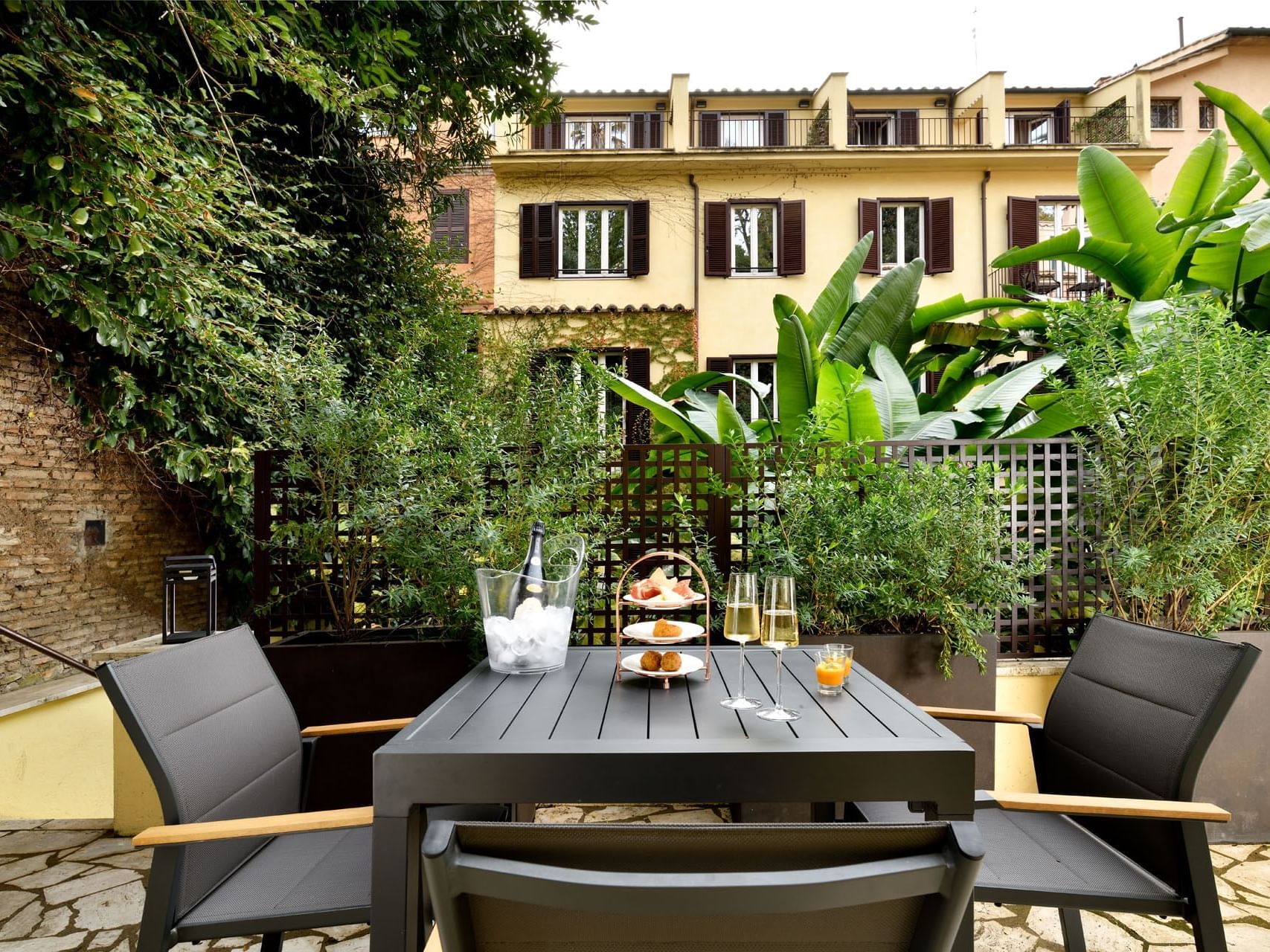 Patio dining area with table set and lush greenery in Garden Suite at Margutta 19