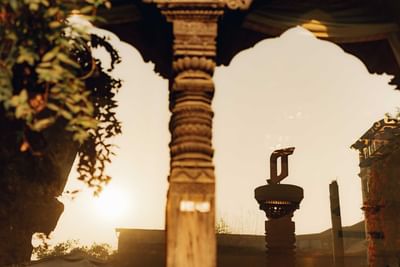 Serene sunset reflecting on ornate temple pillars, surrounded by lush greenery, and warm at The Dwarika’s Hotels and Resorts
