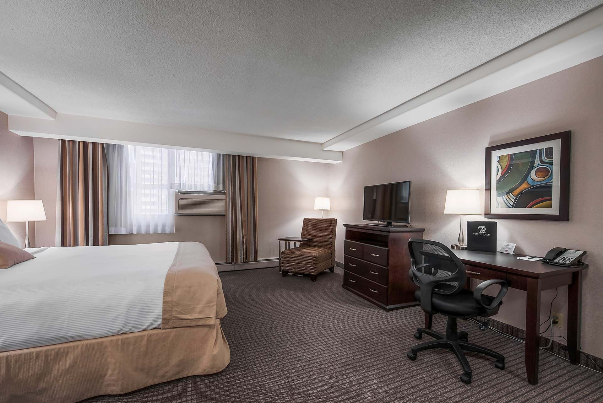 King bed with chair, tv, and work desk in our studio room