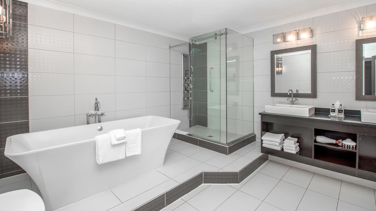 Modern bathroom with freestanding tub, glass-enclosed shower, and floating vanity at Coast Calgary University Area Hotel by APA