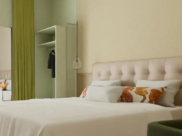 Chambre lumineuse avec lit capitonné beige et coussins décoratifs au Flore Hôtel & Jardin