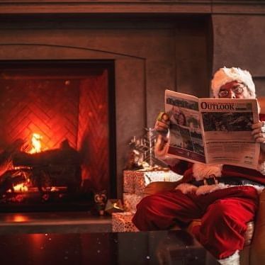 Santa Claus reading paper by a fireplace at The Malcolm Hotel