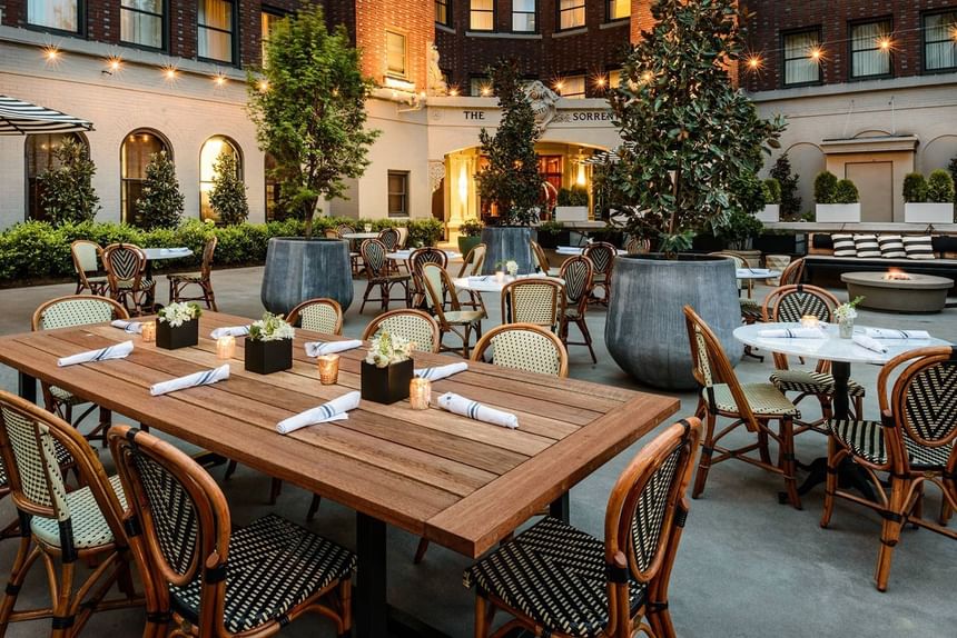 Dining area with wooden tables and woven chairs in The Garden at Hotel Sorrento