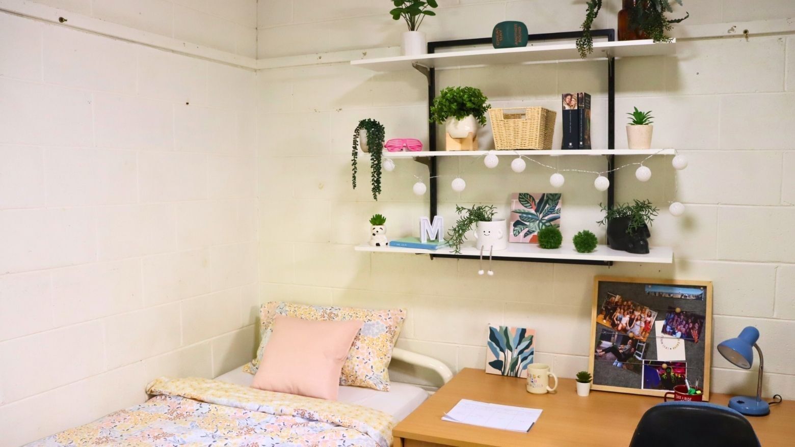 A cozy room with a bed, desk, and shelves with plants at La Trobe University - Units.
