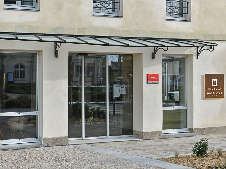 Entrée moderne avec portes en verre et auvent à Hôtel Rivella.
