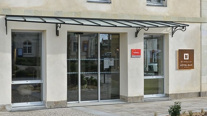 Entrée moderne avec portes en verre et auvent à Hôtel Rivella.