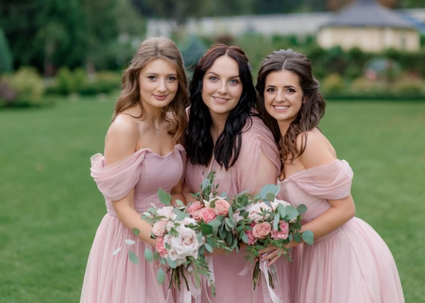 Three bridesmaids posing with bouquets in the garden at The Bethel Resort & Suites