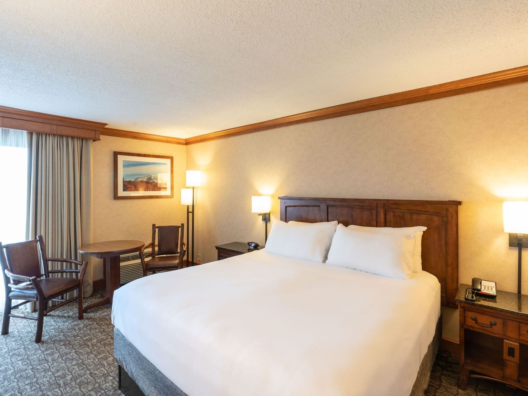 King room with a comfortable bed, a table with chairs and warm lighting at Lake Placid Club Grandview