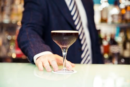 A bartender serving a cocktail at Capital Hotel bar