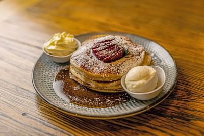 Stack of fluffy pancakes topped with powdered sugar and a strawberry served at Encore By Mingara