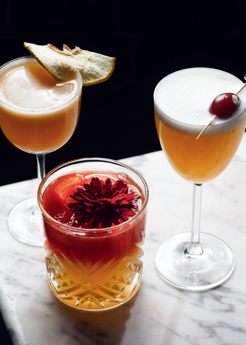 Three fancy cocktails on a marble table with garnishes at Paradox Vancouver