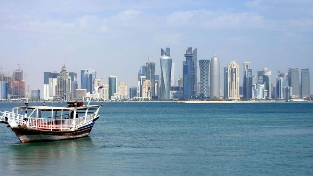 Boat floating in the sea with Doha's skyline in the background.