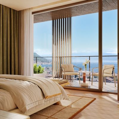 Bedroom with large bed and balcony overlooking the sea and mountains.