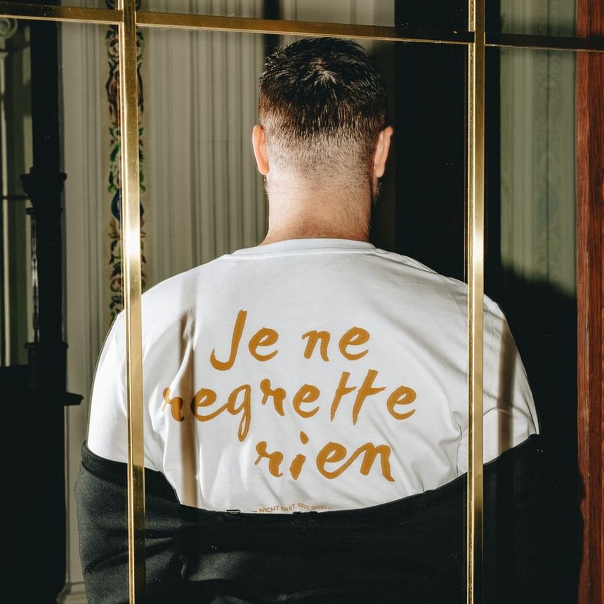 weißes T-Shirt mit goldener Schrift steht vor einem Spiegel bei Hotel Motto Wien