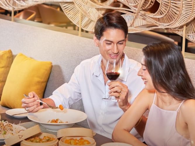 A couple enjoying a meal together at a table with wine and food.