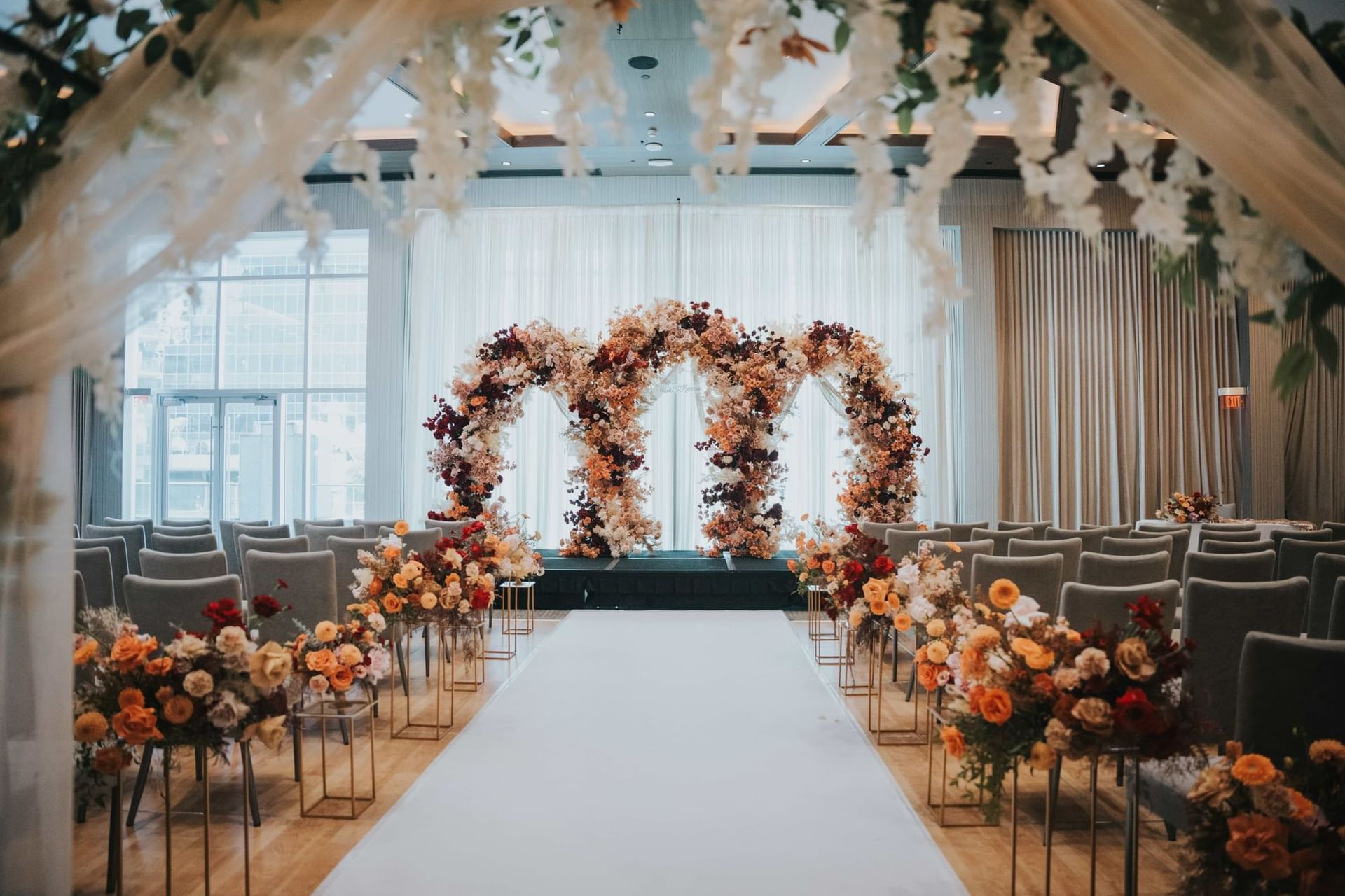 Elegant wedding ceremony setup at Paradox Hotel Vancouver with floral archway, white aisle, and rows of chairs.