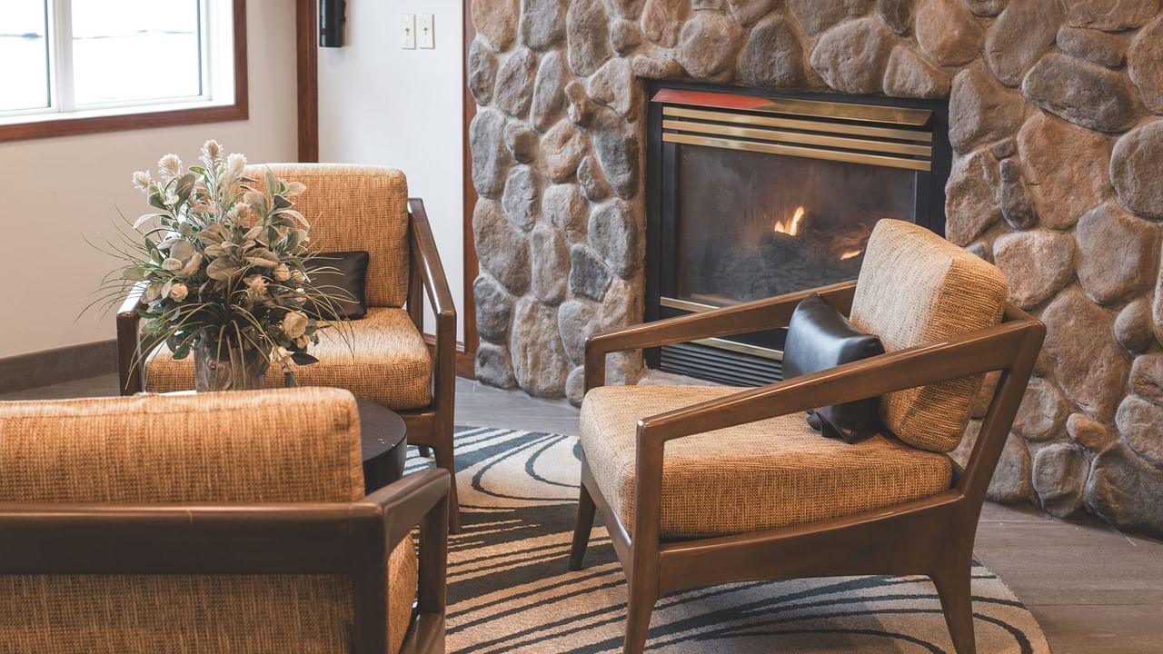 Chairs with cushions and flower arrangement and a fireplace.