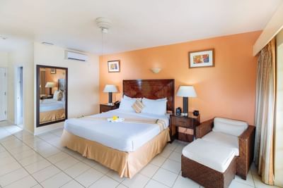 Spacious room with a king-size bed, warm orange walls, and large windows in Jr Executive Suite King at Bay Gardens Hotel