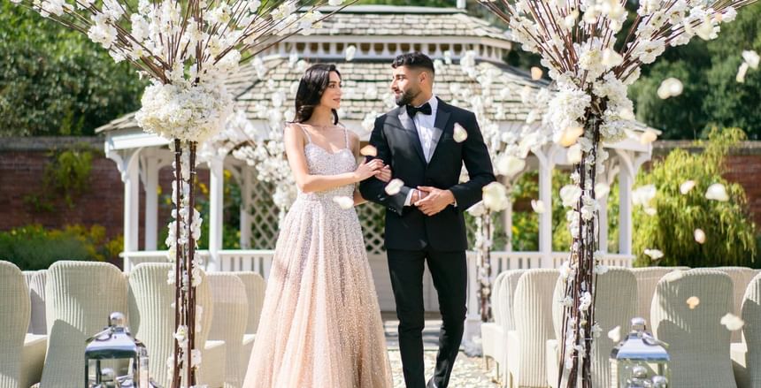 Asian wedding venue in Berkshire featuring just married bride and groom covered in falling flowers