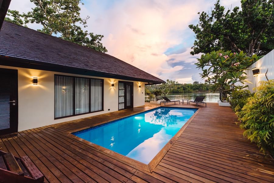 Wooden deck with pool and sun loungers next to a house at Warwick Le Lagon Vanuatu.