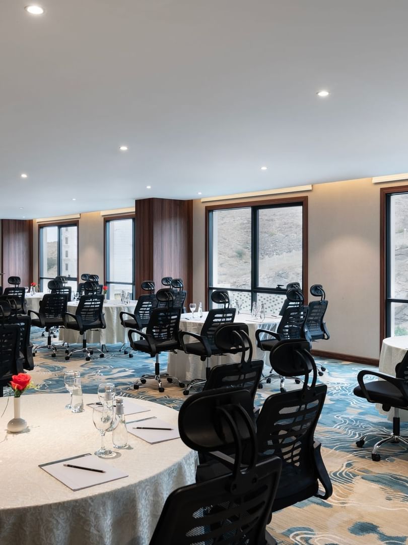 Black office chairs by round tables facing a projector screen  in Amarige Hall at Warwick Hotels and Resorts