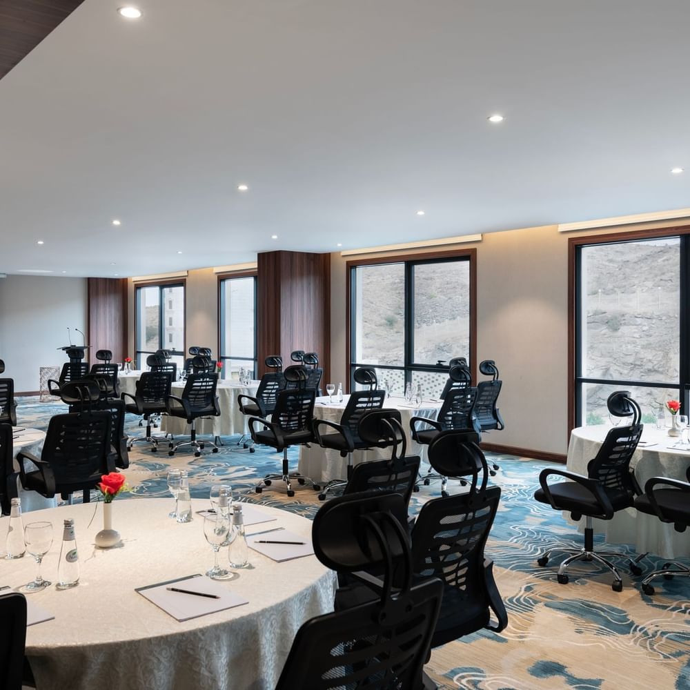 Black office chairs by round tables facing a projector screen  in Amarige Hall at Warwick Hotels and Resorts