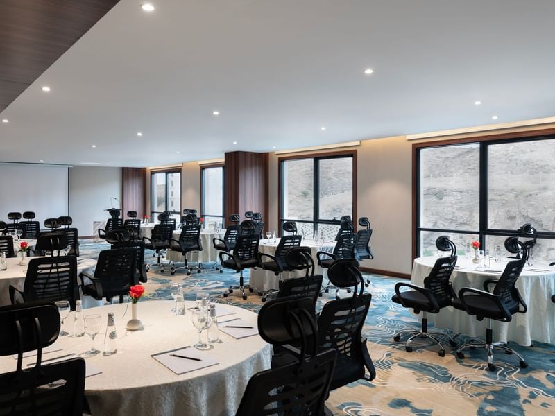 Black office chairs by round tables facing a projector screen  in Amarige Hall at Warwick Hotels and Resorts