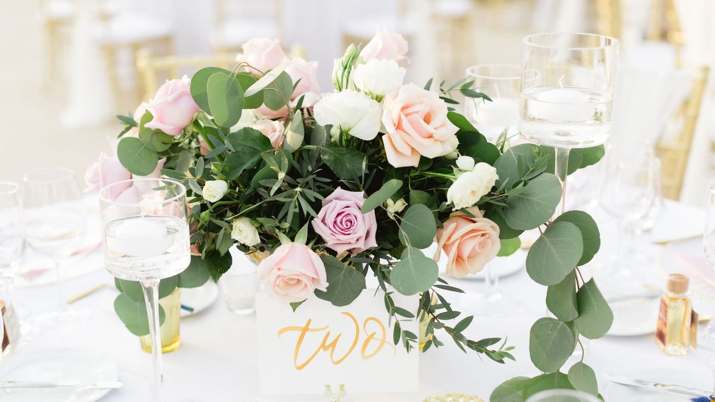 Elegant wedding centerpiece with pink and white roses, greenery, and floating candles at Fiesta Americana Travelty