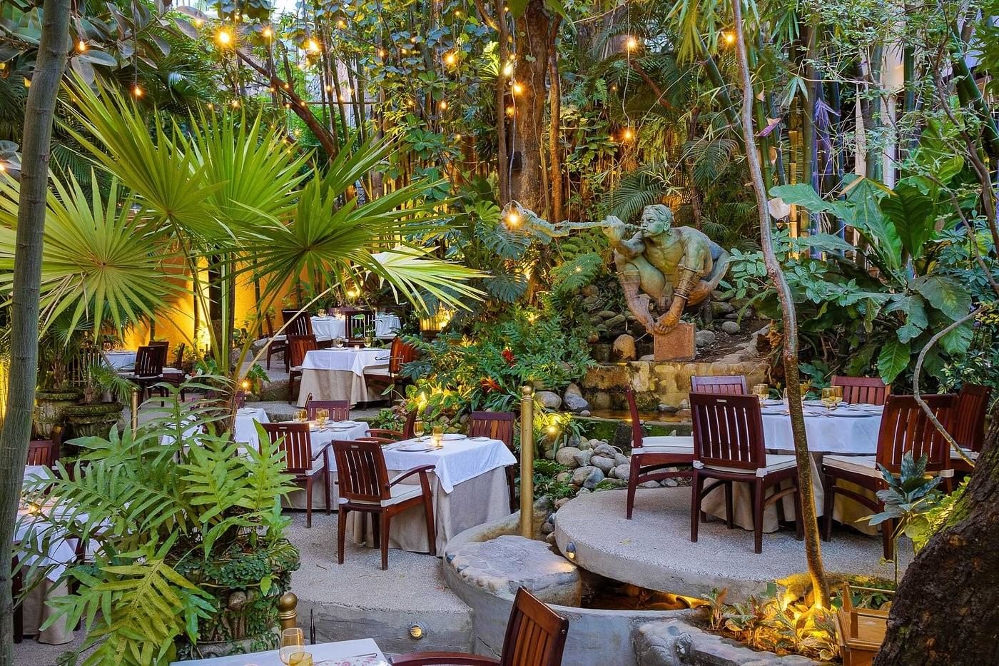 Outdoor restaurant patio surrounded by lush greenery at Almar Resort a premier gay hotel and resort in Puerto Vallarta Mexico