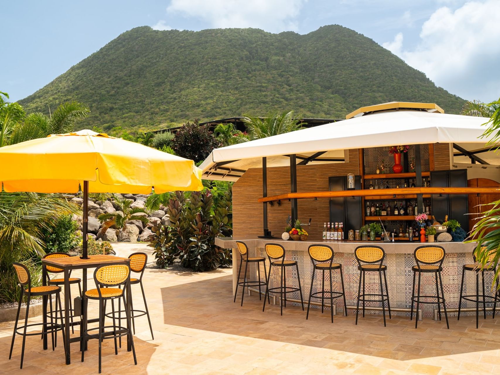Buitenaanzicht van Pool Bar met gele parasols, omgeven door weelderig groen en bergen bij Golden Rock Resort