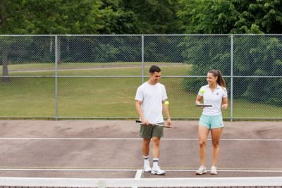 Couple walking on a court by a tall chain-link fence at Rodd Brudenell River Resort, a premier place to stay in PEI