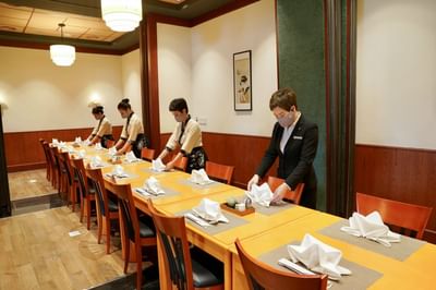 Staff arranging tables in the dining area at Hanoi Daewoo Hotel
