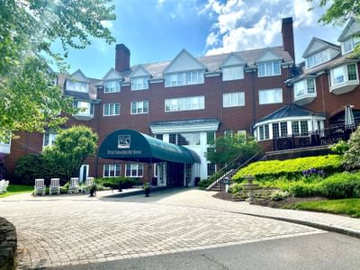The Simsbury Inn exterior features red brick architecture with bay windows and a green awning with the hotel name