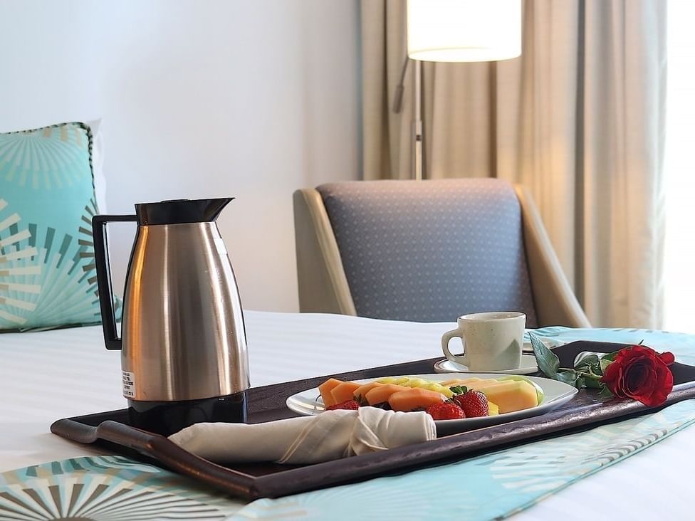 tray of food and coffee on bed with accent chair