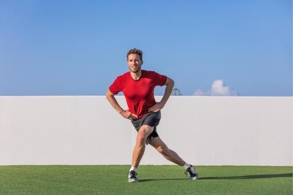 Man performing the curtsy lunge.