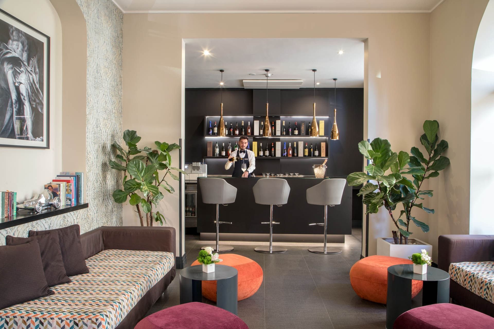 Bar area with modern stools, colorful ottomans, and stocked with various beverages at The Republic Hotel