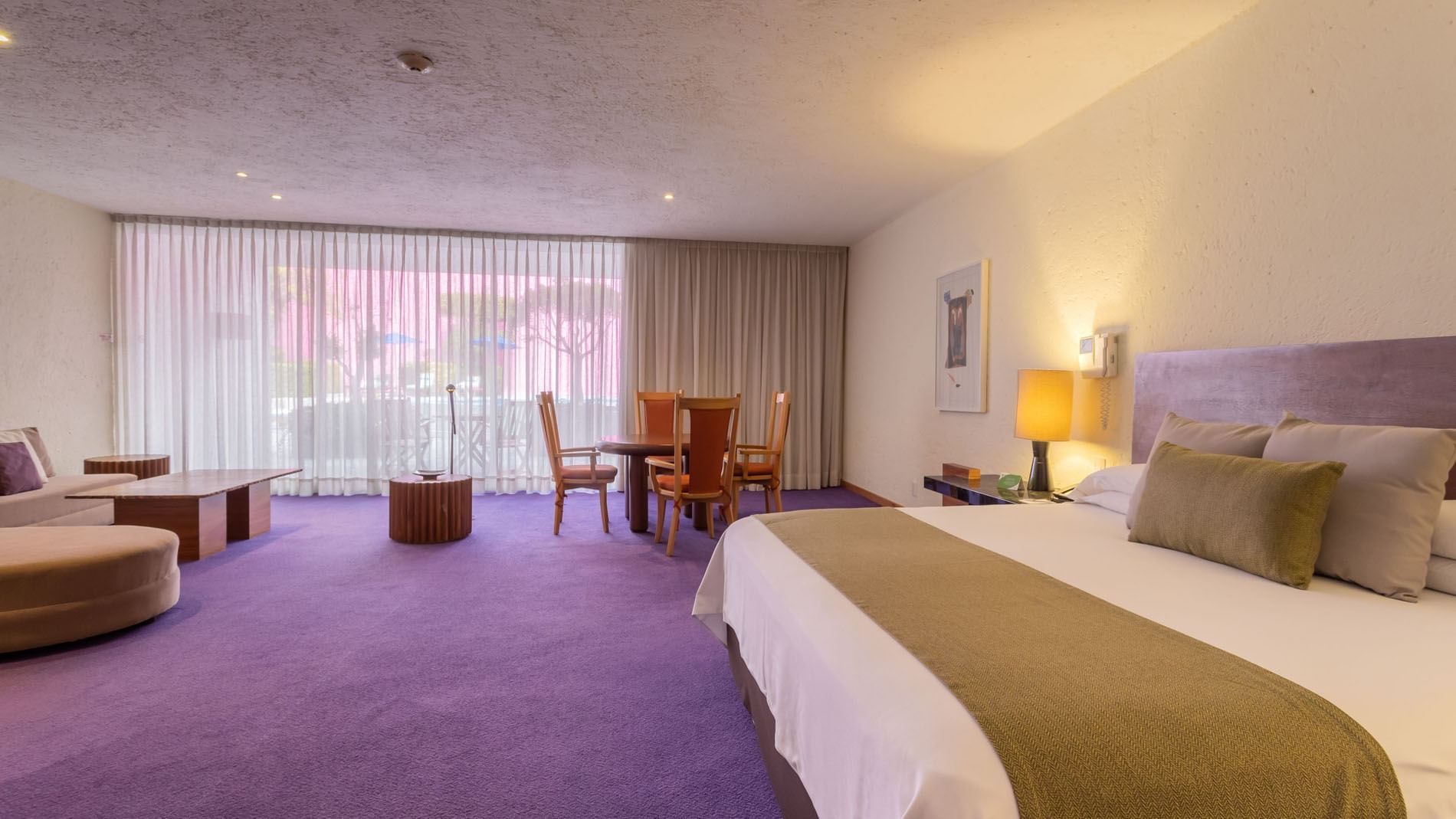 Suite King Fiesta con alfombra púrpura, mesa de comedor y gran ventana en Camino Real Polanco México