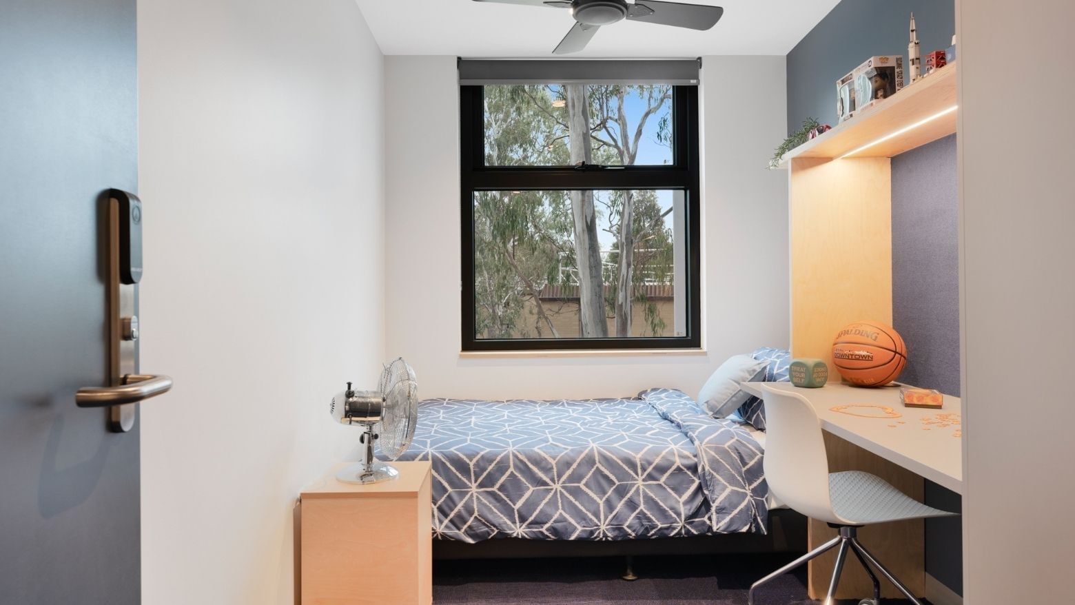 A cozy room with bed, desk, chair, and window at La Trobe University - North and South Apartments.