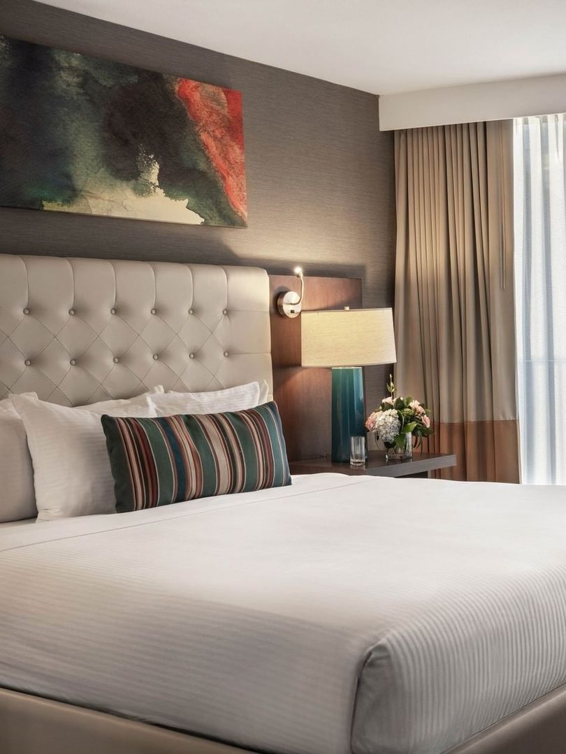 Magnolia Suite with an armchair by a window and a tufted bed under art at Warwick Seattle