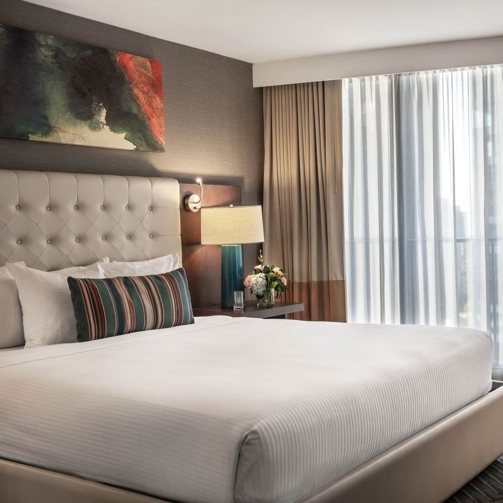 Magnolia Suite with an armchair by a window and a tufted bed under art at Warwick Seattle