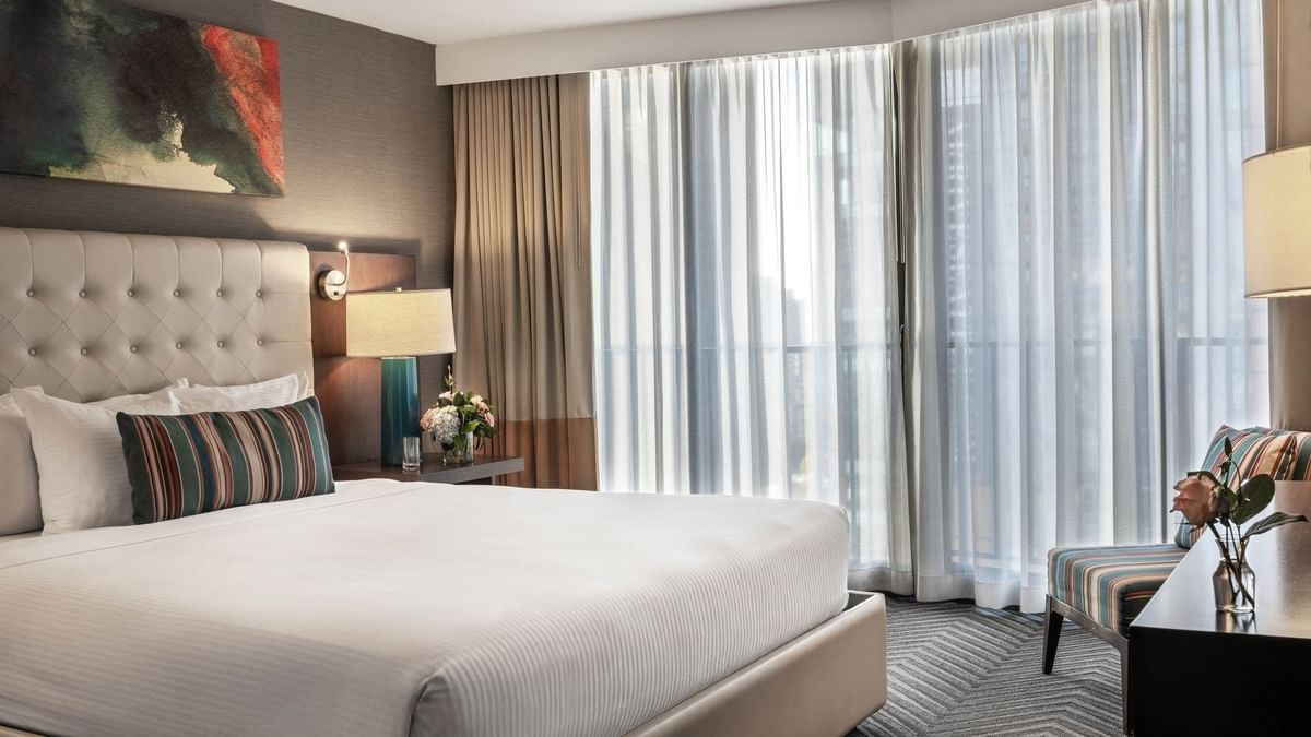 Magnolia Suite with an armchair by a window and a tufted bed under art at Warwick Seattle