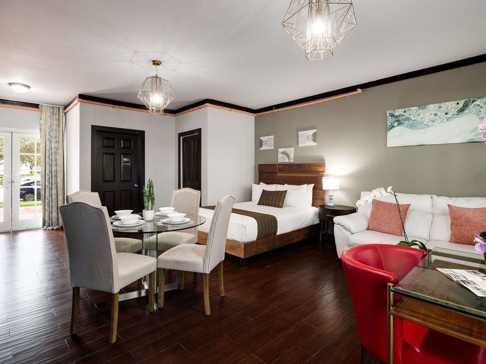 a wide view of a hotel room with a bed, sofa, and dining table