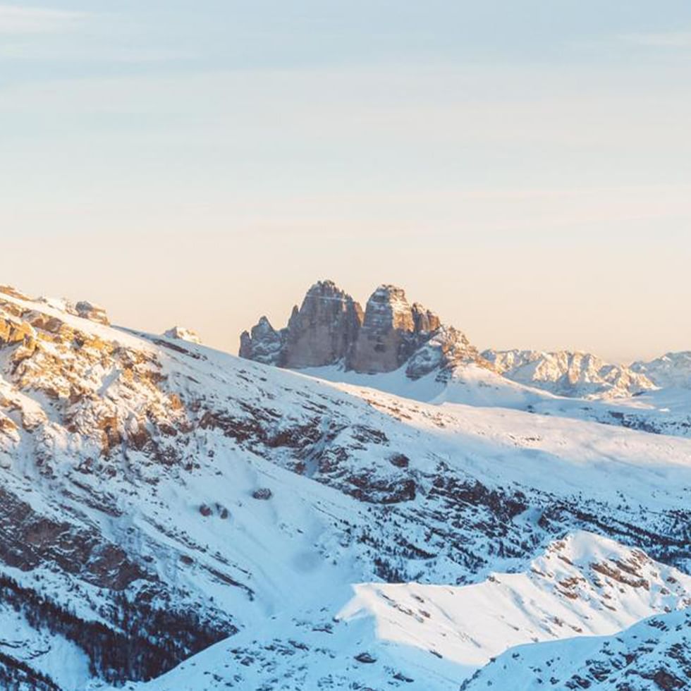 Schneebedeckte Berglandschaft mit klarer Sicht auf die Gipfel und dem Himmel im Hintergrund.