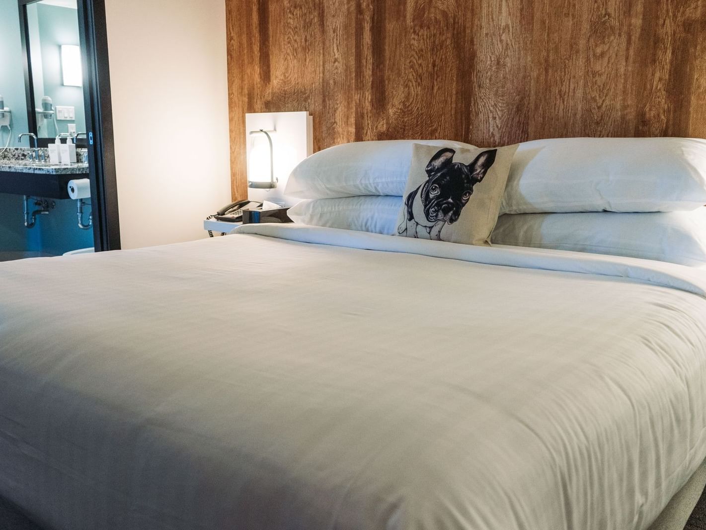 Cozy white bed in room with wooden wall