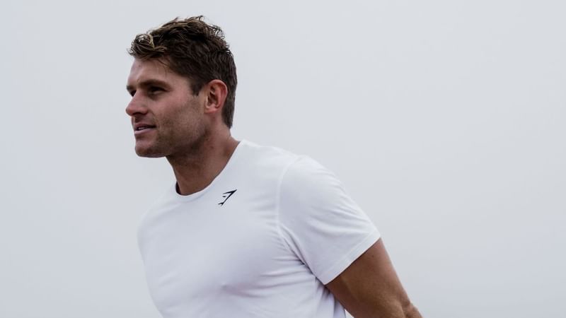 Man stretching leg muscles on a railing by the sea for Sculpt & Strength event.