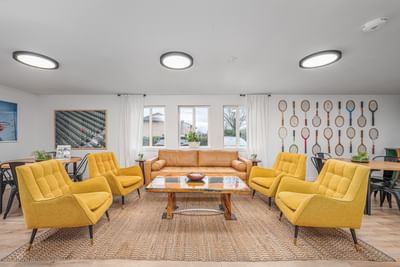 Modern living room with plush seating, a wooden dining table, and tennis racquet wall art at The Varsity North