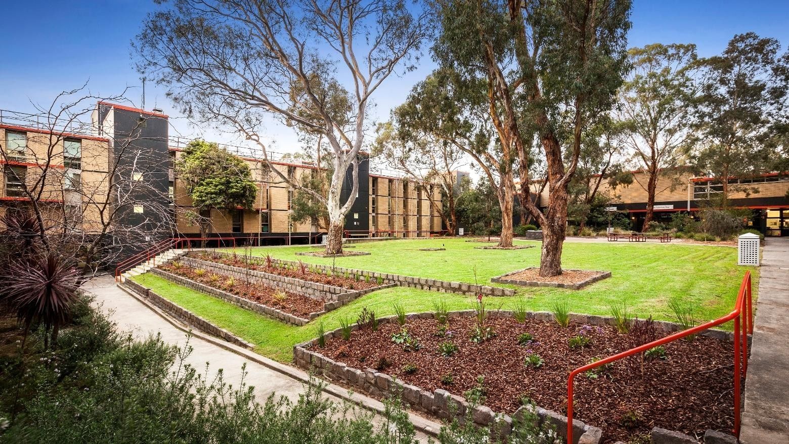 La Trobe University Menzies College buildings and gardens with a red handrail on the right.