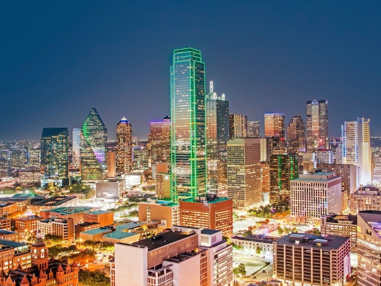 dallas skyline at dusk with a building outlined by green lights in the center